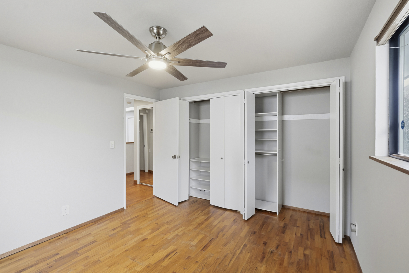Bedroom with ceiling fan, closets, and hardwood floors